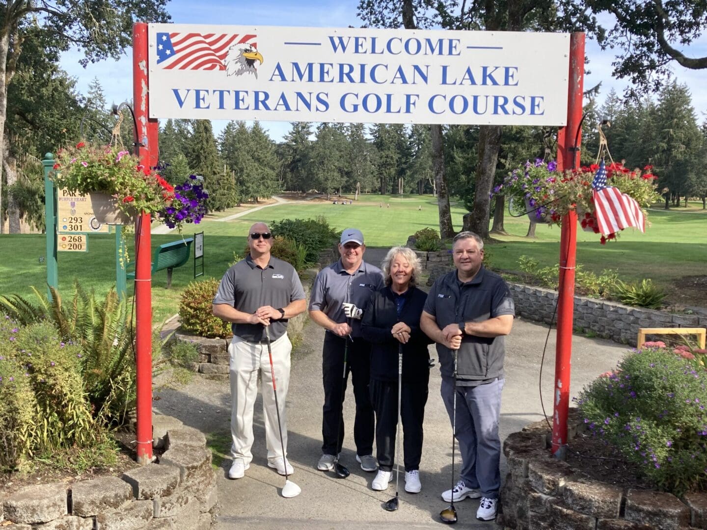 Four people wearing gray uniforms while holding their golf clubs